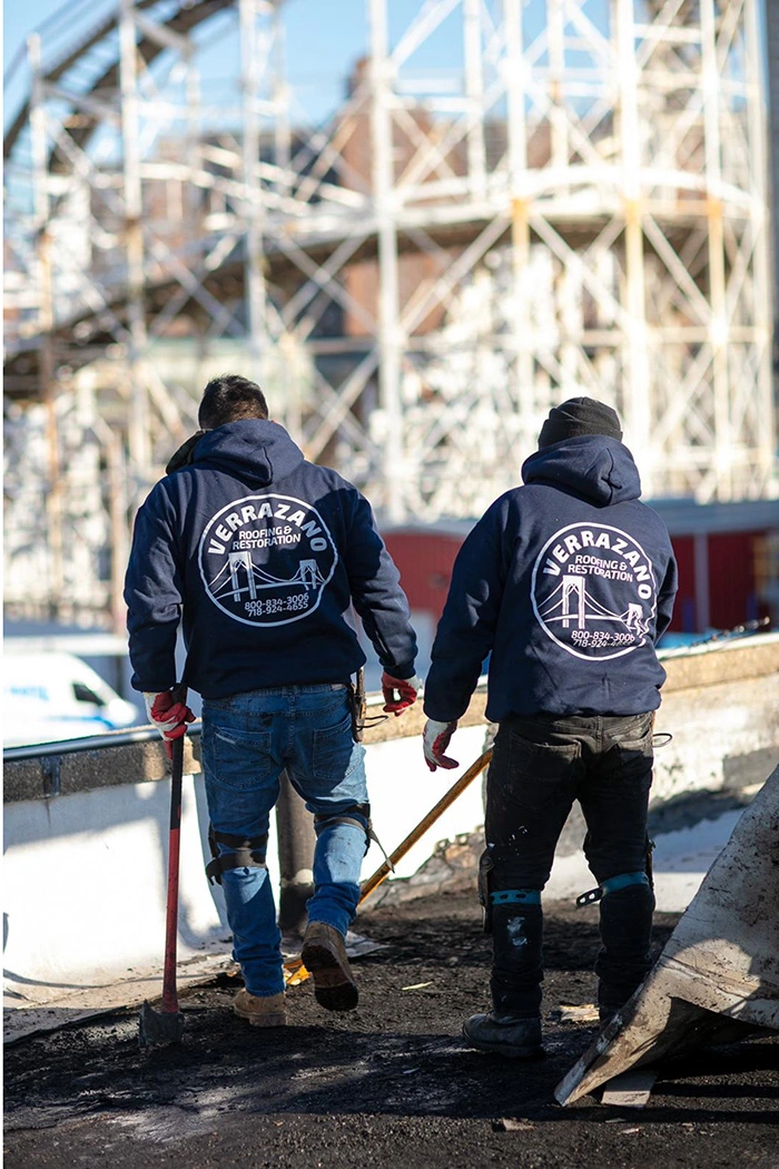 Two Verrazano roofers walking together on a Coney Island rooftop