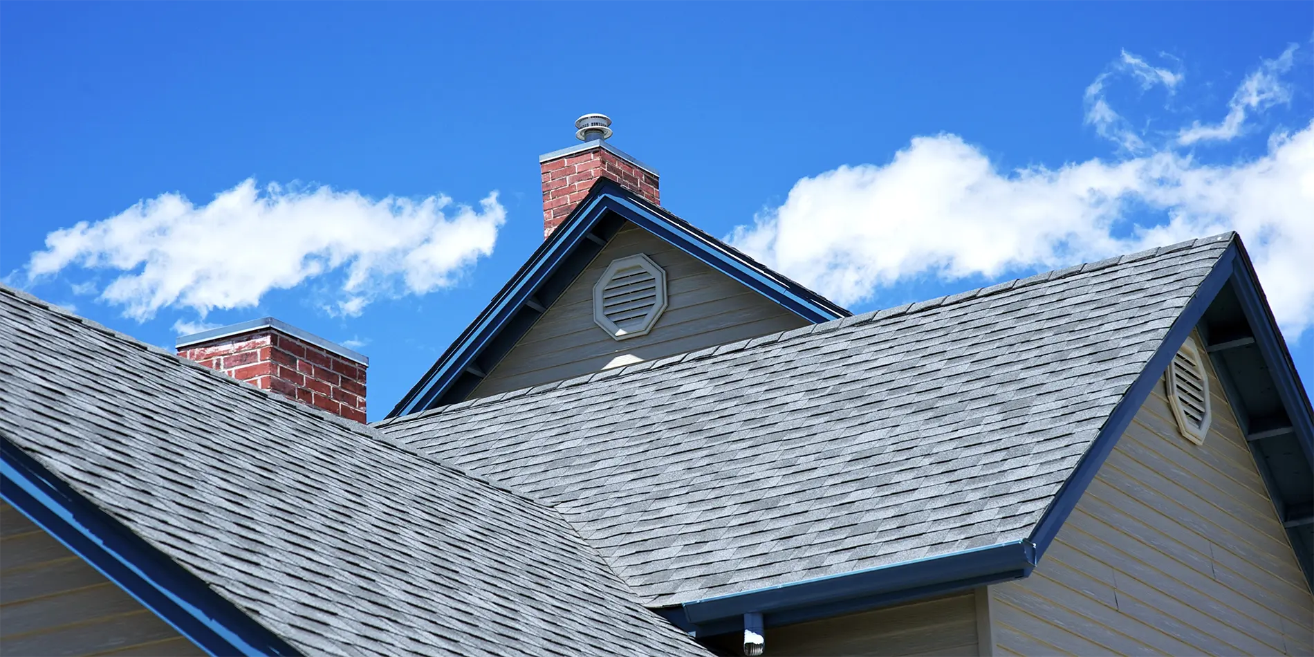 Shingle roof showing intersecting slopes, a chimney and the gutter edge